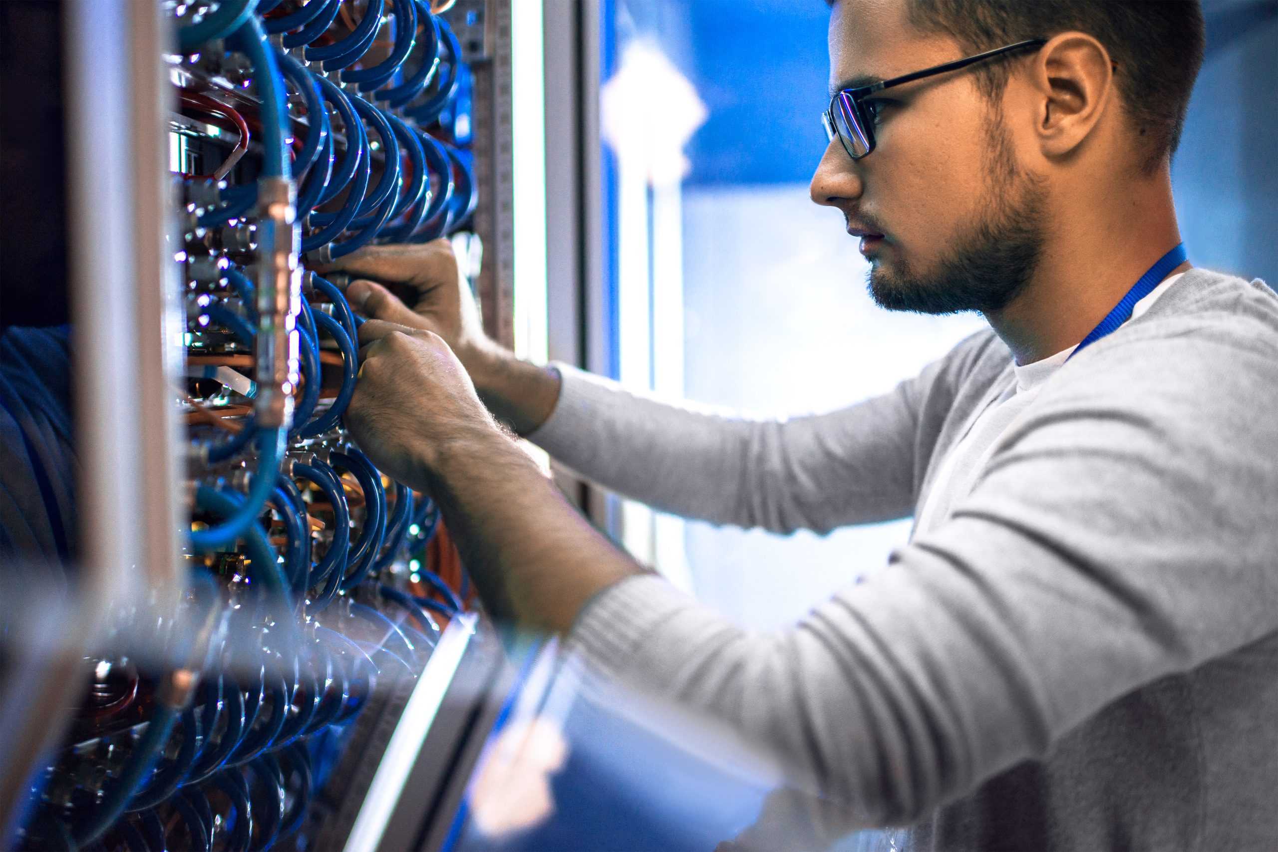 An IT professional working on cords connected to a server.